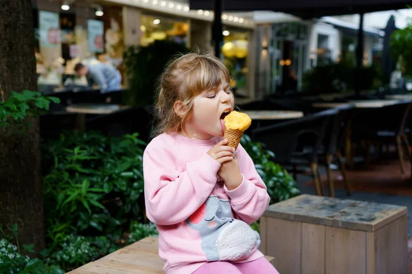 Little preschool girl eating ice cream in waffle cone on sunny summer day. Happy toddler child eat icecream dessert. Sweet food on hot warm summertime days. Bright light, colorful ice-cream — Stock Photo, Image