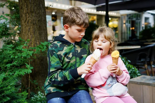 ワッフルコーンでアイスクリームを食べる小さな就学前の女の子と学校の少年幸せな子供たち、弟と妹はアイスクリームデザートを食べます。市内の家族。恋の兄弟. — ストック写真
