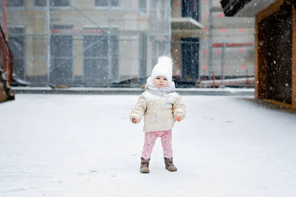 快乐的小女孩在冬天的雪地里迈出了第一步。可爱的幼儿学习走路。孩子们在寒冷的雪天玩得很开心.婴儿的第一场雪，活动。冬季户外散步 — 图库照片