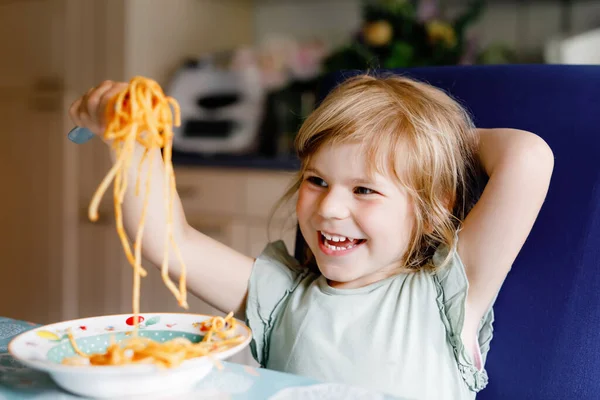 Очаровательная малышка ест спагетти с томатным болоньезе с мясом. Счастливый ребенок дошкольного возраста едят свежие приготовленные здоровые блюда с лапшой и овощами дома, в помещении. — стоковое фото