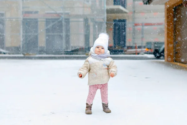 快乐的小女孩在冬天的雪地里迈出了第一步。可爱的幼儿学习走路。孩子们在寒冷的雪天玩得很开心.婴儿的第一场雪，活动。冬季户外散步 — 图库照片