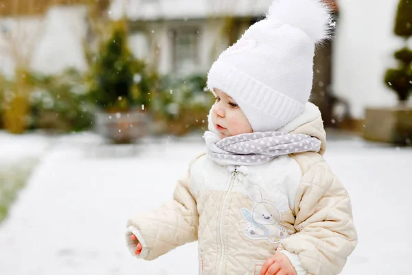 Ragazzina felice fare i primi passi all'aperto in inverno attraverso la neve. Bel bambino che impara a camminare. Bambino che si diverte nella fredda giornata innevata. I bambini prima neve, attività. Passeggiata invernale all'aria aperta — Foto Stock