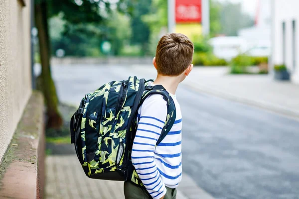 サッチェルと眼鏡をかけた幸せな子供の男の子。中学や高校に行く途中で眼鏡をかけている小学生。学校の庭の外で興奮した子供。学校に戻る. — ストック写真