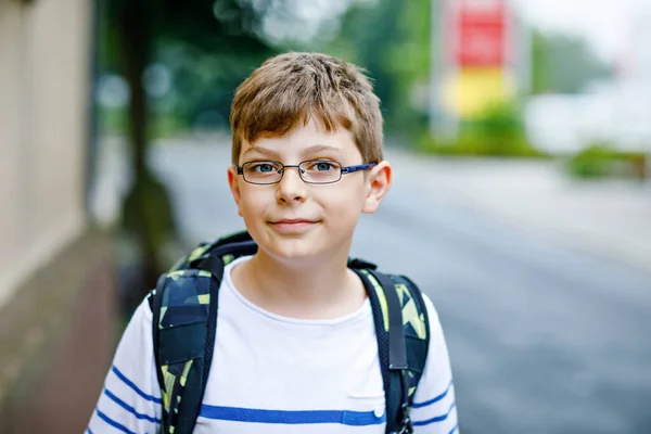 Çantalı ve gözlüklü mutlu çocuk. Ortaokula ya da liseye giderken gözlük takan bir öğrenci. Okul bahçesinde heyecanlı bir çocuk. Okula geri dön.. — Stok fotoğraf