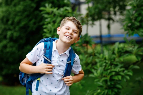 Rapazinho feliz com mochila, a andar. Um estudante a caminho do liceu ou do liceu. Criança excitada ao ar livre no pátio da escola. De volta à escola. — Fotografia de Stock