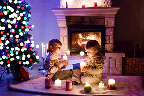 Söta småpojkar, blonda tvillingar som leker tillsammans och ser brinnande ut i skorstenen. Familjen firar jul semester — Stockfoto