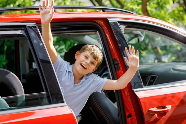 Criança feliz, menino da escola sentado no carro antes de sair para férias de verão com os pais. Criança feliz pela janela do carro que vai na viagem, viagem de estrada da família — Fotografia de Stock