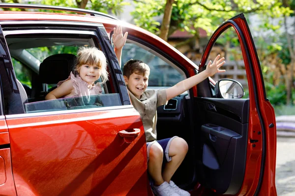 Két gyerek, iskolás fiúk ülnek a kocsiban, mielőtt elmennek nyaralni a szülőkkel. Boldog gyerekek, testvérek, testvérek és barátok az ablakok autó megy az utazás, családi kirándulás — Stock Fotó