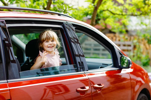 Enfant heureux, petite fille préscolaire assise en voiture avant de partir pour des vacances d'été avec les parents. Joyeux enfant par fenêtre de voiture en voyage, voyage en famille — Photo