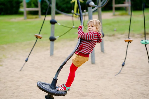 Pequena menina pré-escolar jogando no parque infantil ao ar livre. Criança feliz criança escalando e se divertindo com a atividade de verão ao ar livre. — Fotografia de Stock