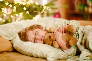 Noel ağacının altında uyuyan ve Noel Baba 'yı evde, evde hayal eden tatlı sarışın çocuk. Geleneksel Hıristiyan festivali. Mutlu çocuk Noel 'de hediye bekliyor. Samimi yumuşak ışık