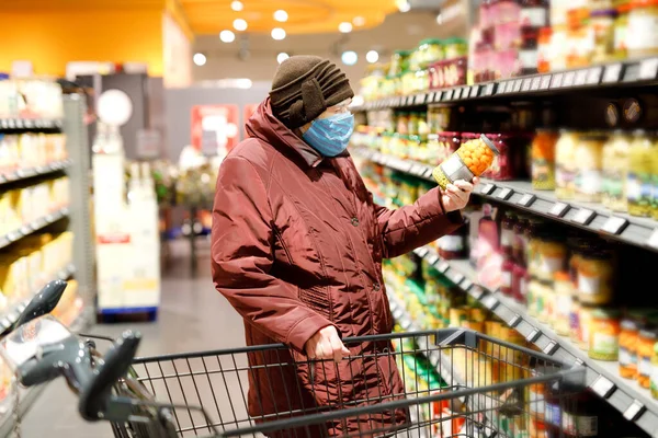 Oude oudere vrouw draagt een medisch masker, bescherming tegen pandemische coronavirus ziekte. 90 jaar gepensioneerde vrouwelijke dame duwen kar trolley om te winkelen in de supermarkt. Vrouw koopt eten en boodschappen — Stockfoto
