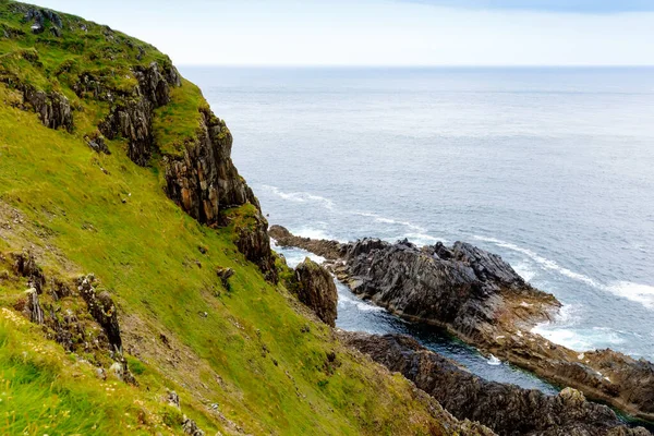 Paesaggio accidentato a Malin Head, contea di Donegal, Irlanda. Spiaggia ruvida con scogliere, verde terra rocciosa con pecore nella nebbiosa giornata nuvolosa. — Foto Stock