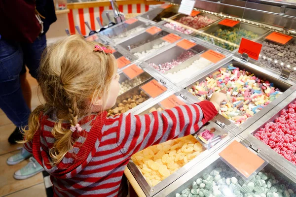 Petite fille d'âge préscolaire dans un magasin de bonbons. mignon heureux tout-petit enfant acheter différents bonbons et sucette dans un magasin. — Photo