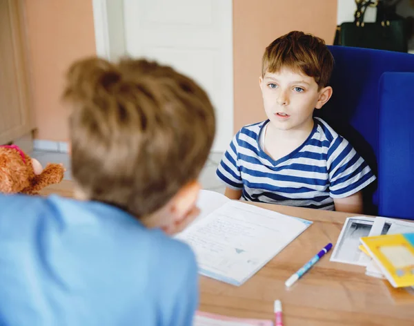 Due ragazzi laboriosi della scuola che fanno i compiti durante la quarantena per una pandemia coronarica. Bambini, fratelli che scrivono con la penna, che rimangono a casa. Concetto di istruzione a casa . — Foto Stock