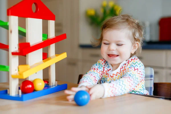 Little baby girl playing with educational toys at home or nursery. Happy healthy toddler child having fun with colorful wooden toy ball track. Kid learning to hold and roll balls. Motoric education. — Stock Photo, Image