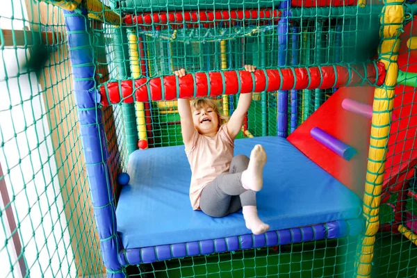 Petite fille active jouant dans une aire de jeux intérieure. Joyeux enfant d'âge préscolaire joyeux grimper, courir, sauter et s'amuser avec des boules en plastique colorées. Activité intérieure pour les enfants. — Photo