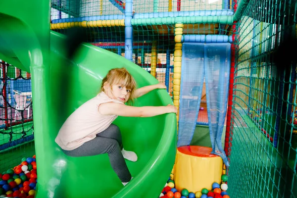 Petite fille active jouant dans une aire de jeux intérieure. Joyeux enfant d'âge préscolaire joyeux grimper, courir, sauter et s'amuser avec des boules en plastique colorées. Activité intérieure pour les enfants. — Photo