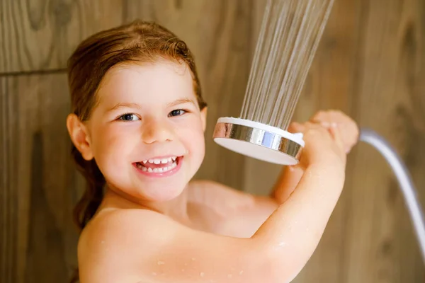 Een klein peutermeisje dat een bad neemt. Gelukkig gezond kleuter spelen met douchekop en water, plezier hebben. Wassen, schoonmaken, hygiëne voor kinderen. — Stockfoto