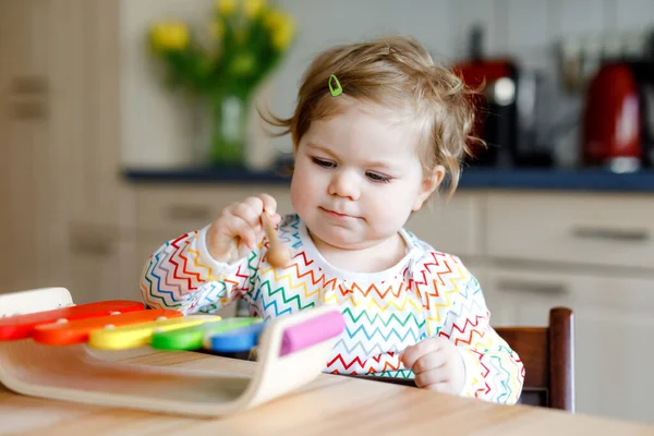 Домашняя симпатичная маленькая девочка, играющая с развивающей деревянной музыкальной игрушкой. Счастливый взволнованный ребенок малыша научиться играть красочные радуги ксилофона. Раннее образование, деятельность для детей. — стоковое фото