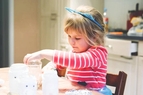 ハロウィンパーティーの幽霊ランタンを作る小さな幼児の女の子。秋祭りのお祝いのための装飾のためのかわいい就学前の子供が手工芸品をやって、自作のキャンドルライトランター. — ストック写真