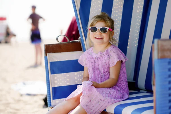 Petite fille d'âge préscolaire reposant sur une chaise de plage. Mignon enfant heureux tout-petit en vacances en famille sur la mer. Enfant jouant, s'amusant en plein air sur le panier de plage en osier sur la côte allemande de la mer Baltique. — Photo