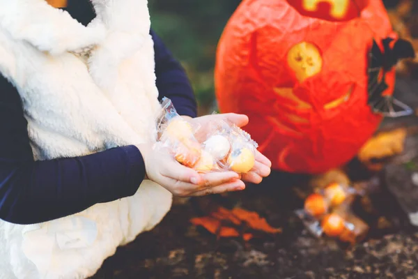 Detailní záběr batolete holka trik nebo dárek na Halloween. Šťastné dítě venku počítá sladkosti z dýňové tašky pro sladké strašení. Rodinná slavnostní sezóna v říjnu. Venkovní aktivita. Trick or treat fun. — Stock fotografie