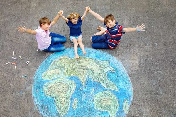 Niña preescolar y dos niños de la escuela con la pintura globo de tierra con tiza de colores en el suelo. Feliz concepto del día de la tierra. Creación de niños para salvar el mundo, el medio ambiente y la ecología. —  Fotos de Stock