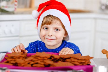 Kreş çocuğu zencefilli kurabiye pişiriyor. Xmas süveter giyen mutlu, yeni yürümeye başlayan çocuk. Mutfak Noel için dekore edildi. Noel aile aktivitesi