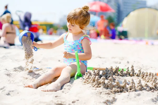 Little preschool girl playing with sand toys on the beach. Cute happy toddler child on family vacations on the sea. Active child having fung on Baltic Sea. Outdoor activity for children — Stock Photo, Image