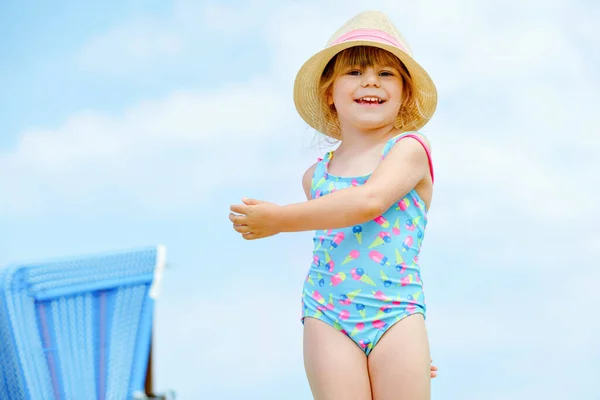 Porträt eines Vorschulmädchens in buntem Badeanzug und Strohhut. Nettes glückliches Kleinkind im Familienurlaub am Meer. Glück, Sommerzeit und Reisen mit Kindern. — Stockfoto