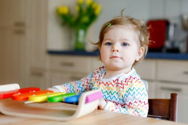 Evde eğitici ahşap müzik oyuncağıyla oynayan sevimli, güzel bir kız bebek. Heyecanlı çocuk renkli gökkuşağı ksilofonu çalmayı öğreniyor. Erken eğitim, çocuklar için etkinlik.
