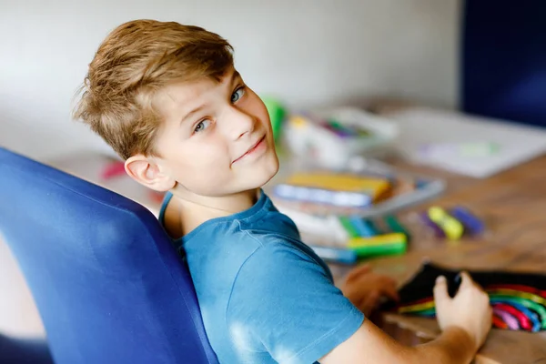 Little school kid boy måla regnbåge med olika pinne färger på svart bakgrund under pandemisk coronavirus karantän sjukdom. Barn målar regnbågar runt om i världen. Glada barn inomhus — Stockfoto