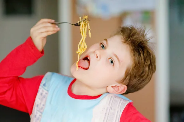 Cute healthy preschool kid boy eats pasta noodles sitting in school or nursery cafe. Happy child eating healthy organic and vegan food in restaurant or at home. Childhood, health concept — Stock Photo, Image