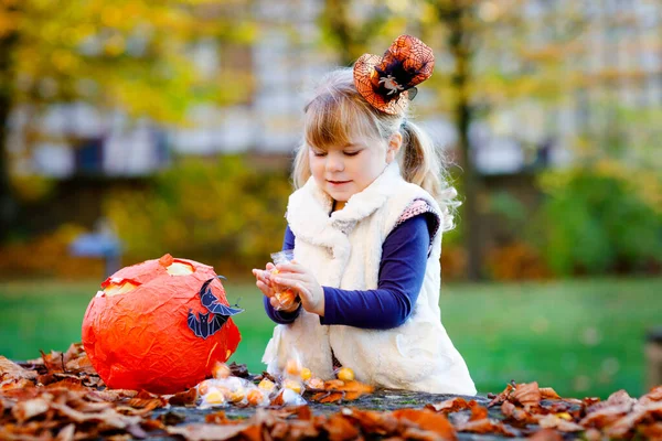 Pequena menina criança vestida como um truque de bruxa ou deleite no Halloween. Criança feliz ao ar livre, com chapéu engraçado laranja e saco de abóbora para assombração doce. Temporada do festival de família em outubro. Actividade exterior — Fotografia de Stock