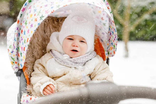 Traurig weinendes kleines Mädchen, das an Wintertagen im Kinderwagen oder Kinderwagen sitzt. Unglücklich verärgerte müde und erschöpfte Kind in warmen Kleidern. Babys erster Schnee. Winterspaziergang im Freien. — Stockfoto