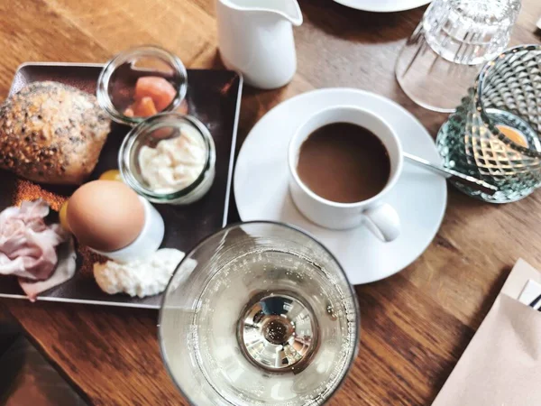 Stół nakryty na śniadanie na zewnątrz latem z różnymi dżemami, chlebem, kawą, rogalikami, jajkami, muesli bekonowymi i sokiem pomarańczowym — Zdjęcie stockowe