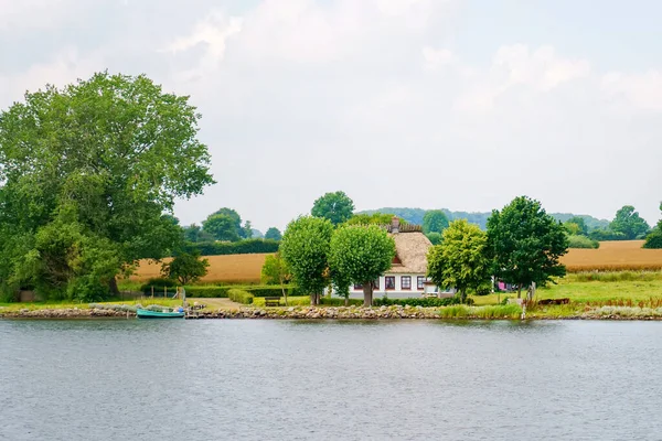 Piękny region Schlei w Niemczech, Szlezwik Holsztyn. Niemiecki krajobraz latem. Rzeka Schlei i typowe domy z strzechą, dachy z trzciny wodnej. — Zdjęcie stockowe