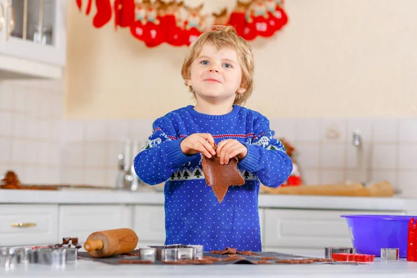 Um miúdo pré-escolar a fazer biscoitos de gengibre. Criança ativa feliz em camisola xmas. Cozinha decorada para o Natal. Atividade familiar de Natal — Fotografia de Stock