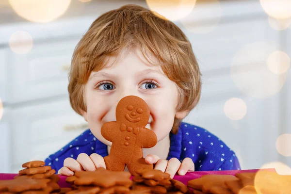 Petit garçon d'âge préscolaire qui fait des biscuits au pain d'épice. Joyeux enfant actif tout-petit en pull de Noël. Cuisine décorée pour Noël. Activité familiale de Noël — Photo