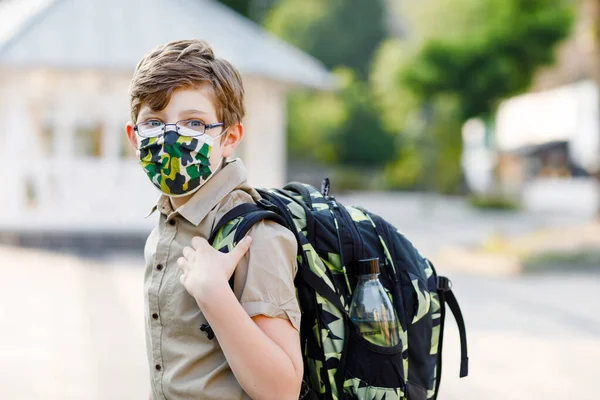 Щасливий хлопчик з окулярами та медичною маскою через пандемію коронавірусу. Школярка з сателітом чекає на автобус на шляху до школи в сонячний день. Здорова дитина на вулиці . — стокове фото