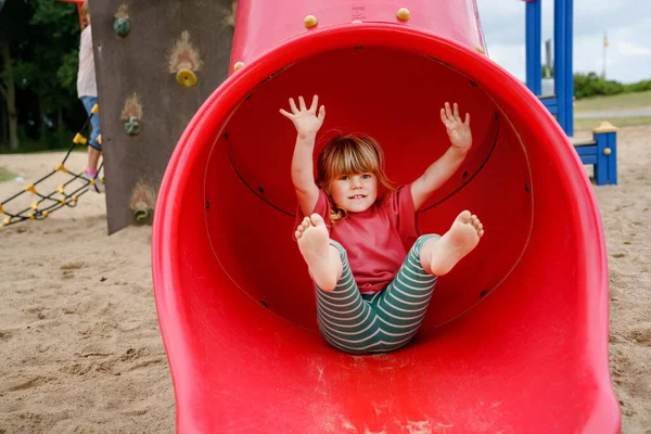 Pequena menina pré-escolar jogando no parque infantil ao ar livre. Criança feliz criança escalando e se divertindo com a atividade de verão ao ar livre. Rapariga a cegar o escorrega. Crianças se divertindo. — Fotografia de Stock