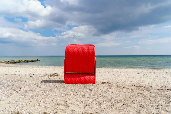 Traditional German roofed wicker beach chairs on the beach of Baltic Sea. Beach with red chairs on stormy sunny day. Ostsee. — Stock Photo, Image