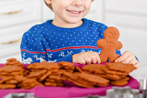작은 미취학 아동 이 생강 쿠키를 굽고 있어. 활성 아기는 xmas 스웨터를 입고 행복 합니다. 부엌은 크리스마스에 장식했고. 크리스마스 가족 활동 — 스톡 사진