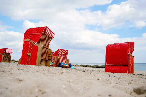 Traditional German roofed wicker beach chairs on the beach of Baltic Sea. Beach with red chairs on stormy sunny day. Ostsee. — Stock Photo, Image