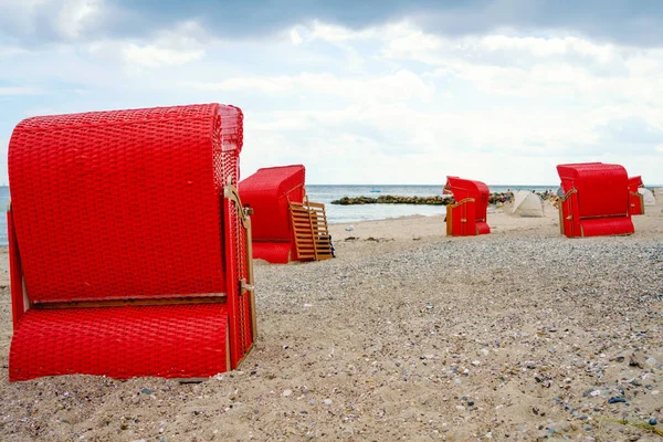 Geleneksel Alman çatı hasır plaj sandalyeleri Baltık Denizi sahilinde. Fırtınalı bir günde kırmızı sandalyeli plaj. Ostsee. — Stok fotoğraf