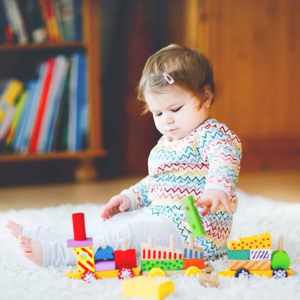 Liten flicka leker med pedagogiska träleksaker hemma eller på dagis. Småbarn med färgglada tåg. Barn som har roligt med olika leksaker. Ensam unge under koronaviruspandemisk karantän — Stockfoto