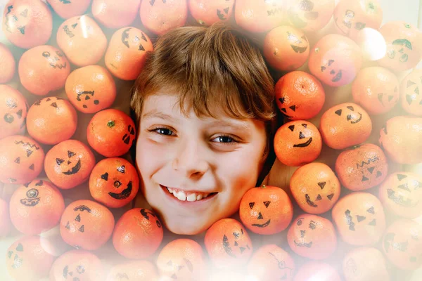 Забавный портрет очаровательного мальчика с апельсиновым мандарином, выглядящим как маленькая тыква-фонарь. Счастливая улыбка ребенка праздник Хэллоуин фестиваль или вечеринка. Создание открыток для друзей. — стоковое фото