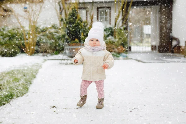 Niña feliz haciendo primeros pasos al aire libre en invierno a través de la nieve. Lindo niño aprendiendo a caminar. Niño divirtiéndose en el frío día nevado. Babys primera nieve, actividad. Paseo de invierno al aire libre — Foto de Stock