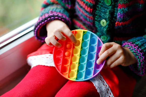 Little blonde preschool girl playing with new trend sensory toy - rainbow pop it. Antistress toy for children and adult. Colorful toy simple dimple. Squishy soft bubble toys rainbow color. Happy child — Stock Photo, Image